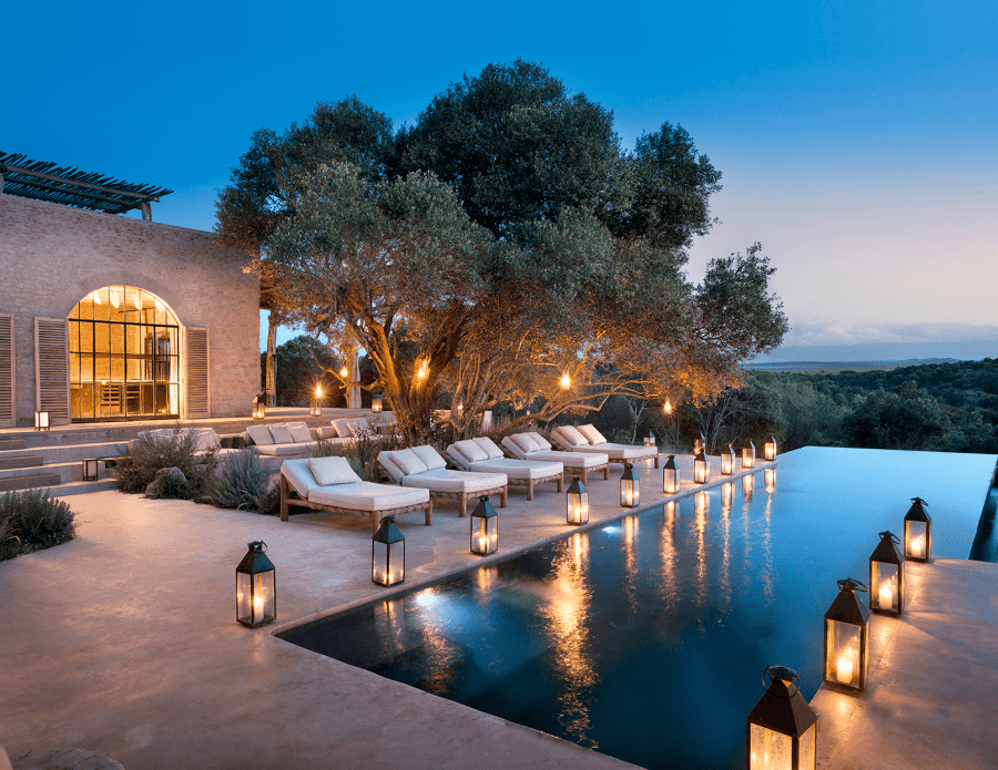 an outdoor patio and pool lit by lanterns at night
